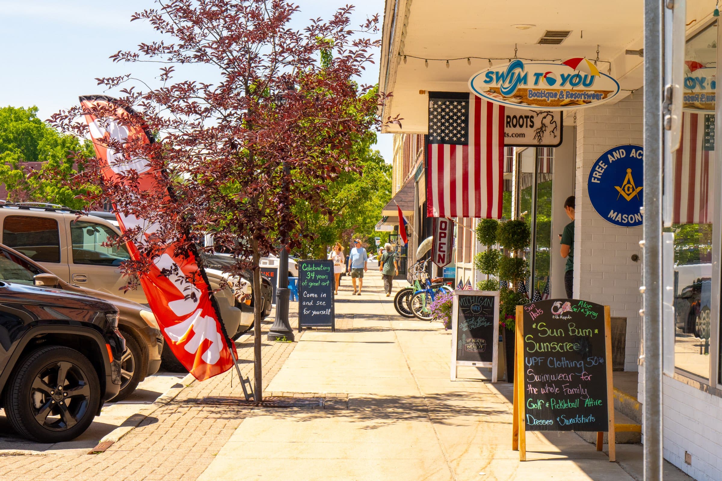 Shopfronts and sidewalk signs along River Street in downtown Elk Rapids